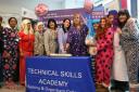 Vicky Knight (centre, lilac onesie) cutting the cake with Hilary Moore, Head of the Technical Skills Academy (centre, purple spotted onesie)